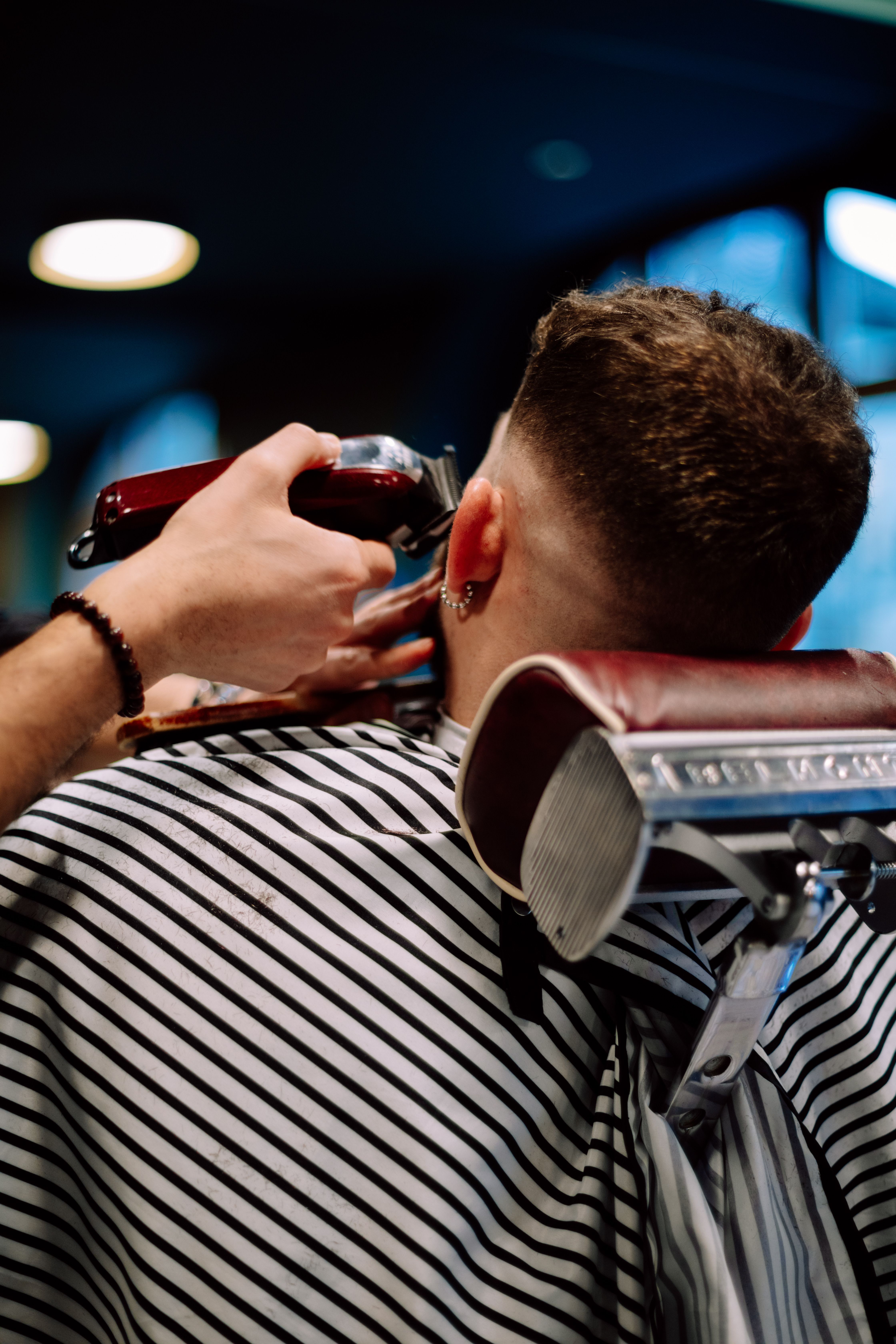Symbolbild: ein Barbier arbeitet mit dem Clipper an einem Haarschnitt